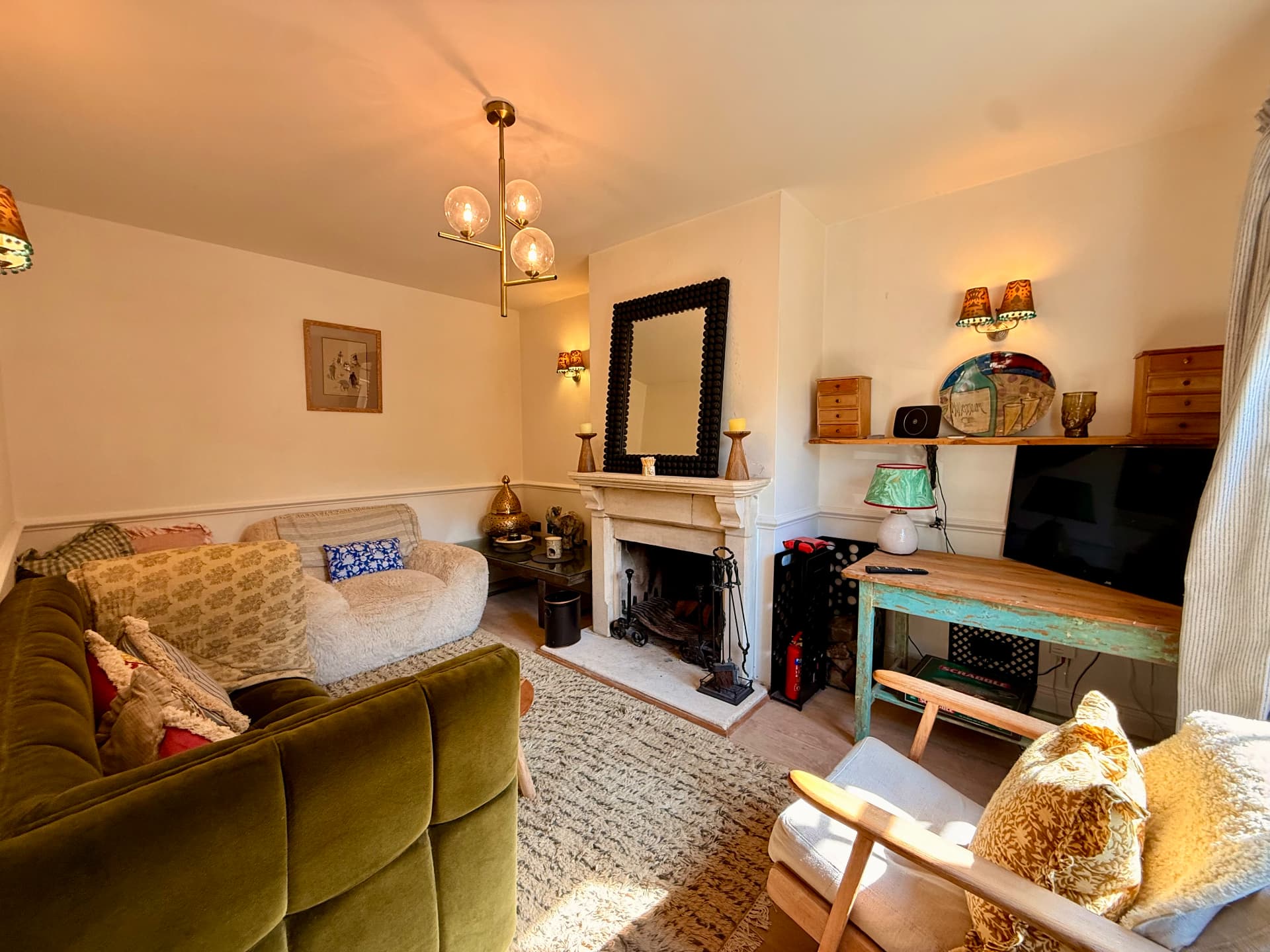 Living room with green velvet sofa and open fireplace
